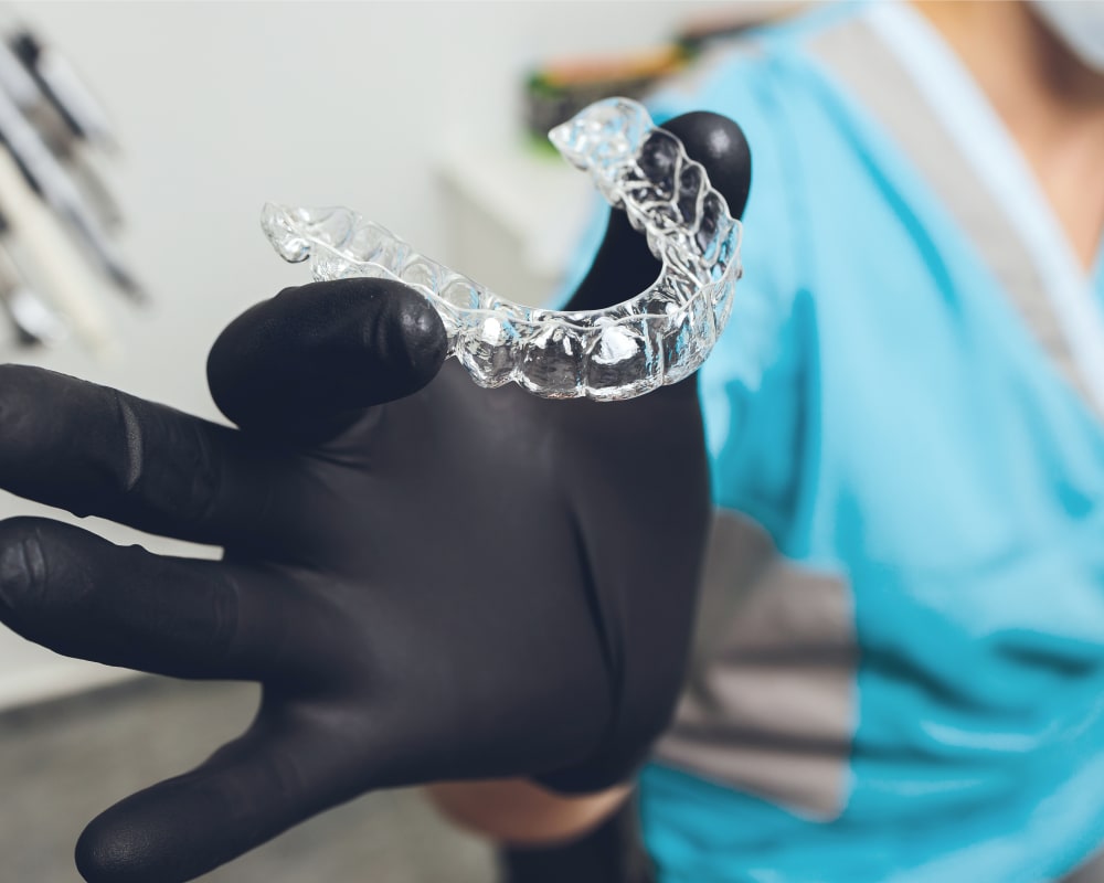 A dental professional holds up a clear aligner tray.