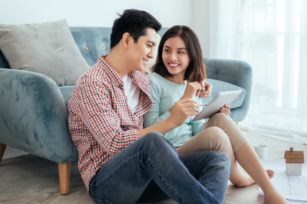 A young couple is sitting snuggled together looking at a tablet.