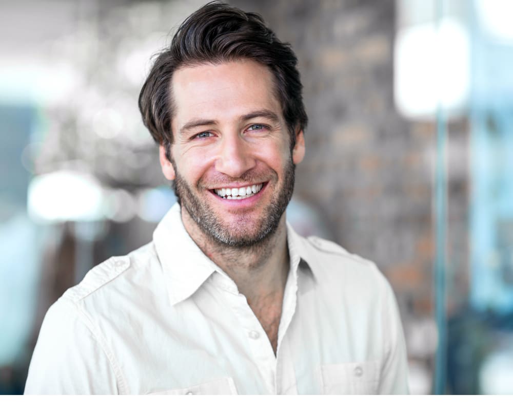 A man is smiling at the camera, showing off his bright white teeth.